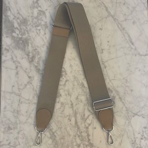 Adjustable beige canvas handbag strap.